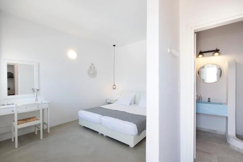 a white bedroom with a bed and a bathroom at Kouros Village in Antiparos Town
