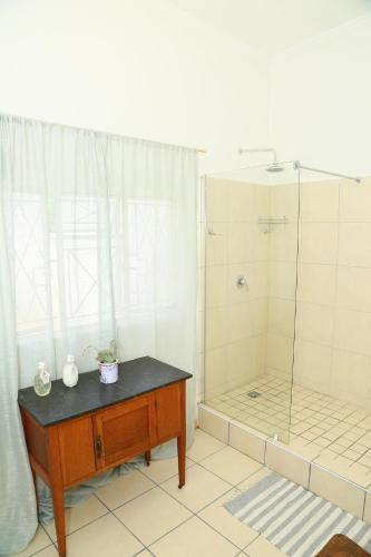 a bathroom with a shower with a wooden table and a wooden table sidx sidx at Die Hoekhuis in Cradock