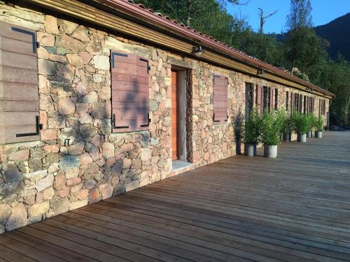 a stone building with a wooden deck next to it at Casa Santa Lucia in Bocognano