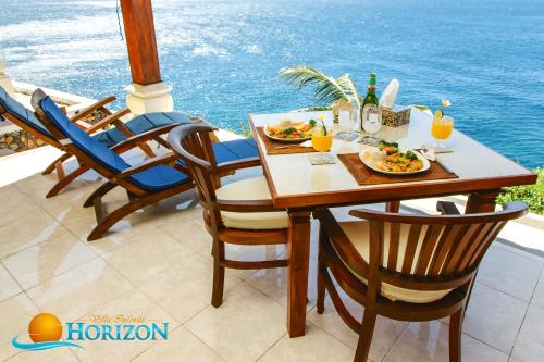 a table with plates of food on a balcony with the ocean at Villa Infinite Horizon in Amed