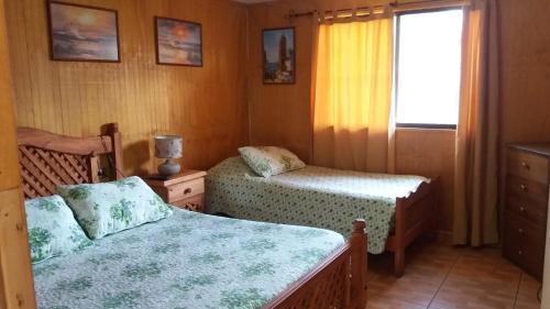 a bedroom with two beds and a window at Hotel San Juan in Coquimbo