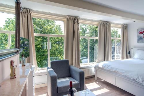 a bedroom with a bed and a chair and windows at The Blue Stairs in Amsterdam