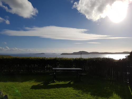 a bench sitting in the grass near the water at Kilmichael House in Drumnadrochit