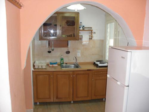 a kitchen with an archway over a sink and a refrigerator at Kahlua in Liapades