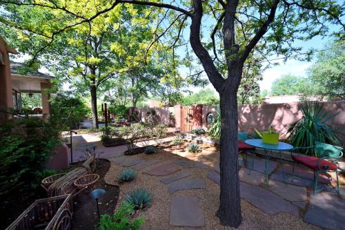 a garden with a table and benches and a tree at Casa Culinaria - The Gourmet Inn in Santa Fe