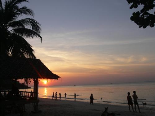 a group of people on the beach at sunset at Ibiza Bungalows in Haad Yao