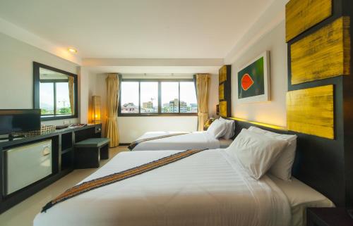 een hotelkamer met 2 bedden en een televisie bij Crystal Inn in Phuket