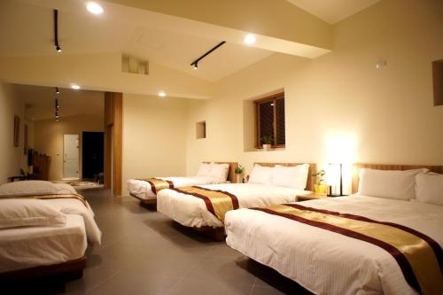 un grupo de 3 camas en una habitación en Simonhall B&B en Tainan