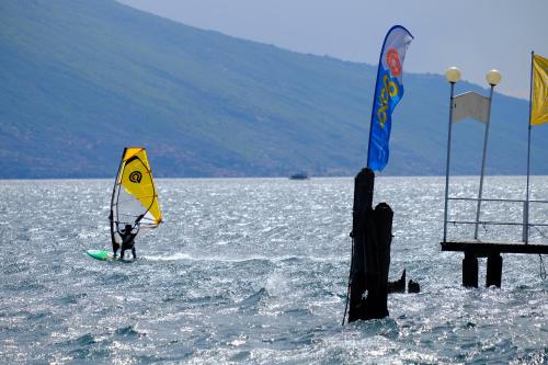 a person is windsurfing in the water near a pier at Hotel Capo Reamol in Limone sul Garda