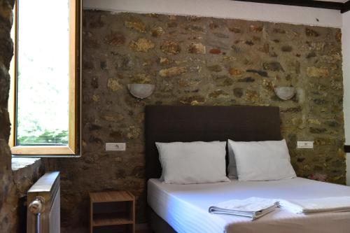 a bedroom with a bed and a stone wall at Canyon Matka Hotel in Matka