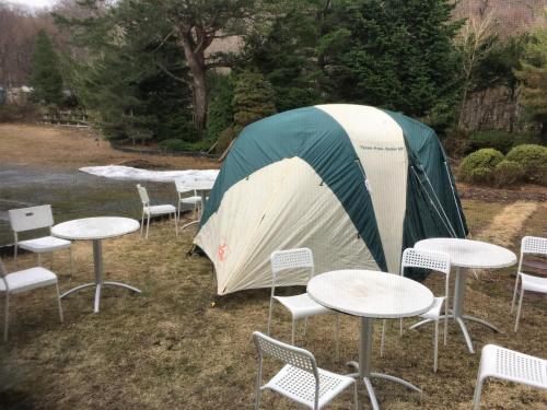 a group of tables and chairs and a tent at Towadako Hostel in Towada