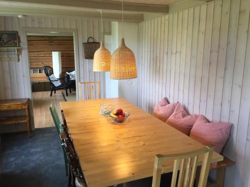 una mesa de madera con sillas y un bol de fruta. en Steigen Lodge Villa Vaag, en Steigen