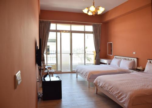ein Hotelzimmer mit 2 Betten und einem großen Fenster in der Unterkunft Red Roof B&B in Taitung