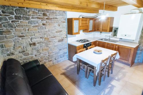 a kitchen with a table and a stone wall at Apartments Casa Vuki in Sečovlje