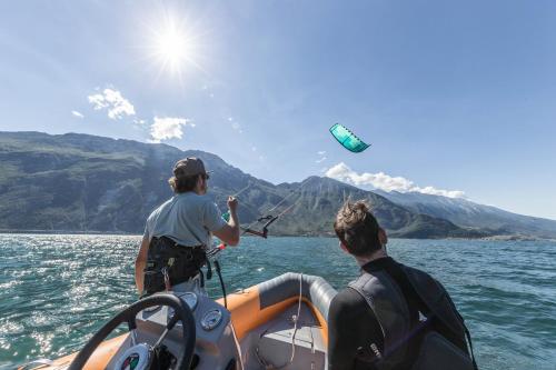 two people on a boat in the water flying a kite at Hotel Capo Reamol in Limone sul Garda