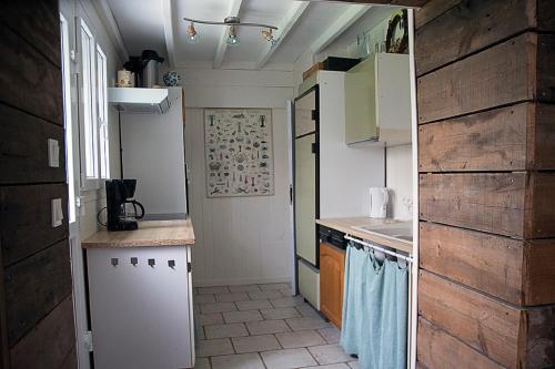 BoufflersにあるLes Gites des Songes de l'Authieの白い家電製品と木製の壁が備わる小さなキッチン