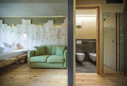 ein Wohnzimmer mit grüner Couch und ein Badezimmer in der Unterkunft Bike & Ski Hotel Diana in Welschnofen
