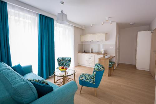 ニエホジェにあるAva Apartamentyのリビングルーム(青いソファ、テーブル付)
