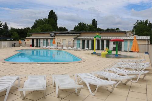 a swimming pool with white chairs and a playground at Mobile Home Hanse in Boofzheim