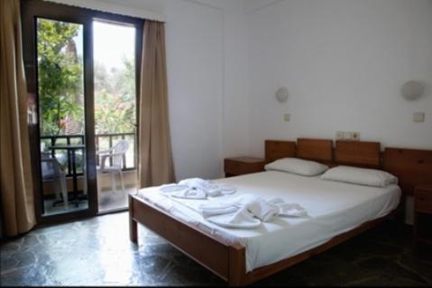 コリンバリにあるPergamos Villageのベッドルーム1室(ベッド1台付)、大きなスライド式ガラスドアが備わります。