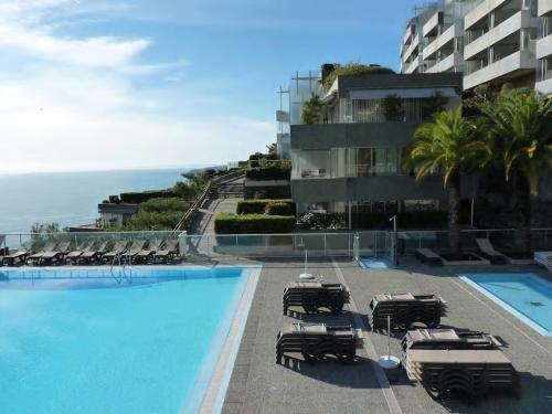 une piscine avec des chaises longues et un bâtiment dans l'établissement Appt 5 personnes vue mer piscine Costa Plana Cap d'Ail Monaco, à Cap d'Ail