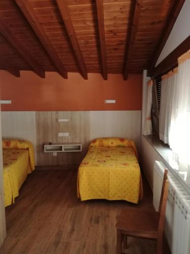 a bedroom with two beds and a wooden floor at Hostal Casa Tino in Caín