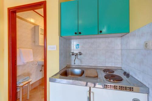a kitchen with a sink and green cabinets at Apartments Josip & Maria in Veli Lošinj