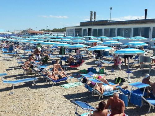 a group of people sitting on the beach under umbrellas at La Casa di Isabella Loreto in Loreto