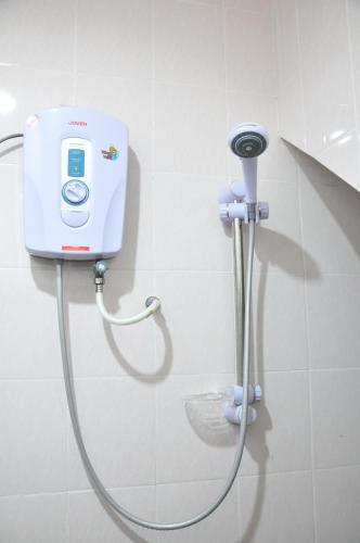 a shower in a bathroom with a phone on the wall at Zeala Asmara Motel in Kuah
