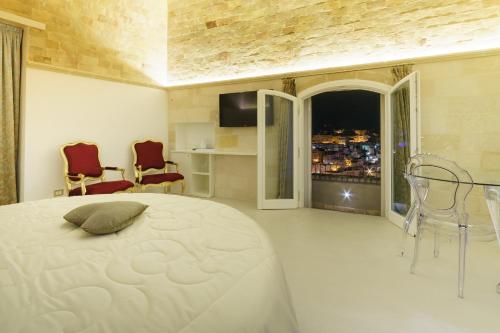 a bedroom with a bed and two chairs and a window at Antica Torre di Iuso in Matera