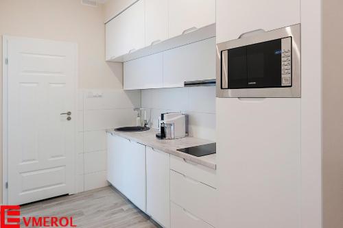 uma cozinha branca com um micro-ondas e um frigorífico em Evmerol Apartment (Hallera) em Breslávia