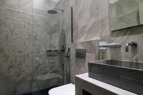 W łazience znajduje się szklana kabina prysznicowa i umywalka. w obiekcie Klities Guest House w mieście Polijiros