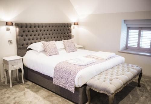 a bedroom with a large bed with a padded headboard at Rutland Water Courtyard Rooms in Oakham