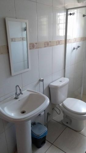 a white bathroom with a sink and a toilet at Pousada Anhanguera in Ribeirão Preto