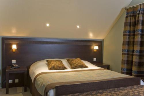 a bedroom with a bed with two pillows on it at Hotel Les Mignees in Barvaux
