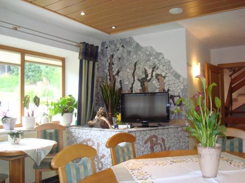 a dining room with a tv on a stone wall at Pension Bartlhof in Lermoos