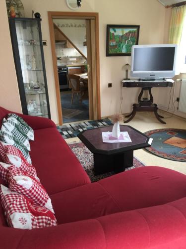 シュネーヴァーディンゲンにあるHaus Claudiaのリビングルーム(赤いソファ、テレビ付)