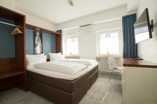 a bedroom with a bed and a desk and two windows at Stern am Rathaus in Cologne