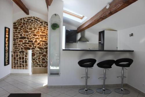 une cuisine avec des tabourets noirs et un mur en briques dans l'établissement Residence Villa Ange, à La Seyne-sur-Mer