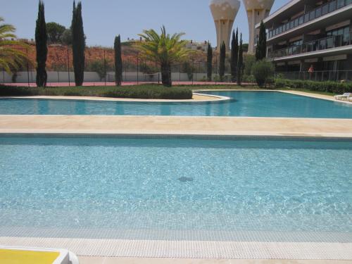 a large swimming pool in a building with trees at Golf Residence Apartment in Vilamoura