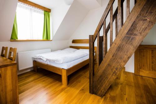 a small bedroom with a bed and a staircase at Penzion U Barana in Trojanovice