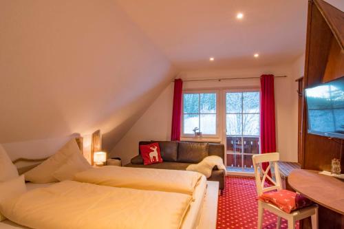 a bedroom with a bed and a couch and a window at Hotel & Restaurant Grüner Baum - Die Grüne Oase Am Feldberg in Feldberg