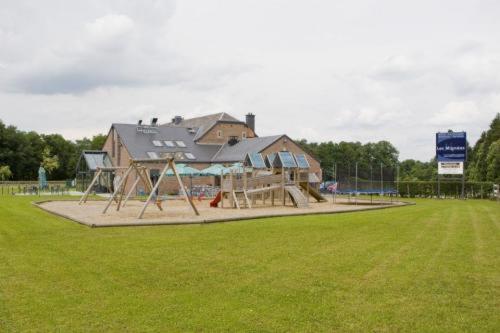 un parque infantil en un campo con una casa en Hotel Les Mignees, en Barvaux