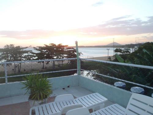 a balcony with white chairs and a view of the beach at Pousada Caravelas in Guarapari