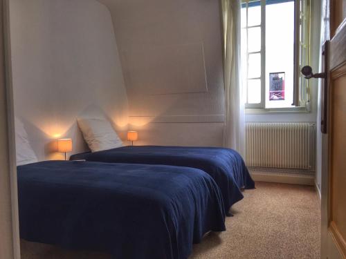 - une chambre avec 2 lits avec des draps bleus et une fenêtre dans l'établissement Villa Yvonnette, à Mers-les-Bains