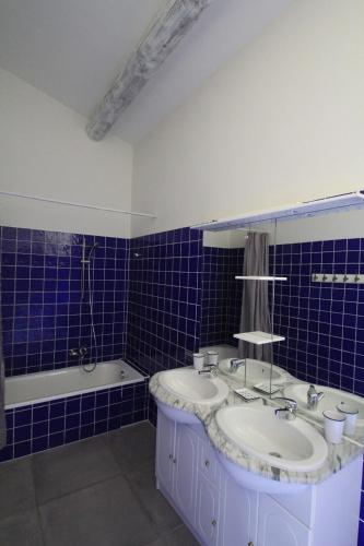 une salle de bain carrelée bleue avec deux lavabos et une baignoire dans l'établissement La Caprine, à Gordes