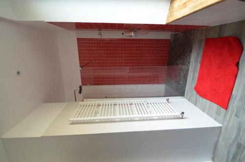 une cuisine avec un mur rouge et une étagère blanche dans l'établissement Villa Le Gai Soleil, à Embrun