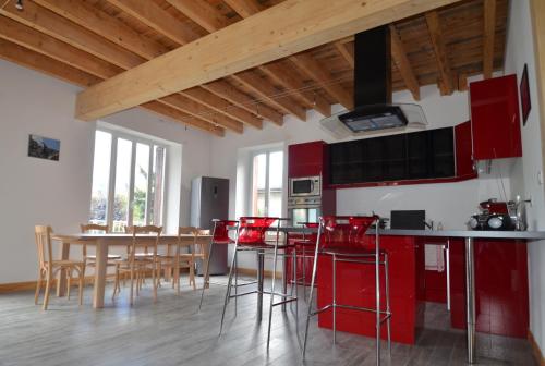una cocina con armarios rojos y una mesa con taburetes en Villa Le Gai Soleil, en Embrun