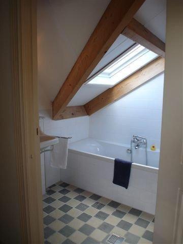 a bathroom with a bath tub and a window at Logement Brocante in De Koog