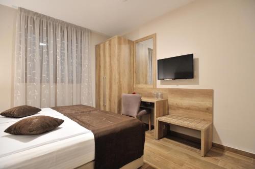a bedroom with a bed and a desk with a television at Villa Divani in Mostar